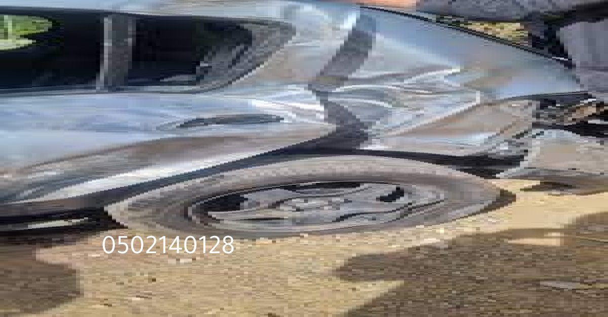 عامل في ورشة بالرياض يقوم بتقويم صاج سيارة متضرر.